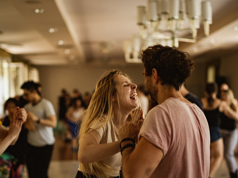 A woman laughing mid dance with her partner on a busy social floor